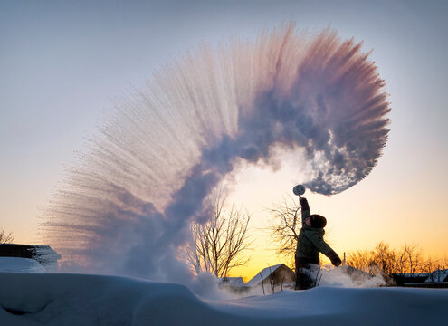 guy splashes boiled water from a thermos over his head against the backdrop of a sunset in frosty weather. The effect of instant freezing of hot water in severe frost. Siberian fireworks experiment