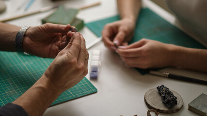 two contemporary working together in jewelry workshop. Master and apprentice. Young male assistant...