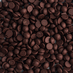 Background texture chocolate drops, close up. Chocolate pieces for dessert decoration.