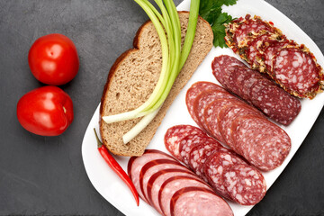 Smoked sausage slices on a white dish with a piece of black bread and onions. Vegetable and meat...