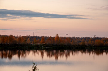 Naklejka premium Sundown and sunrises. Blue sky with tints of purple and much clouds. Silhouettes of trees and grass are reflectioning in the river water. Background of heaven. Beautiful evening