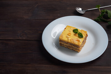 Banana sponge cake with nuts and mint. Delicious sweet dessert for tea, top view, copy space. Dark wooden background.