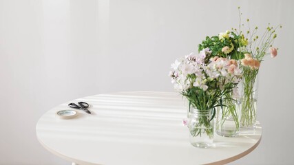 Arreglos florales en agua  con jarra transparente sobre una mesa blanca