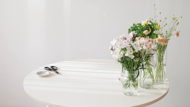 Arreglos florales en agua  con jarra transparente sobre una mesa blanca