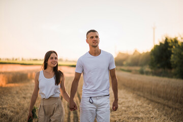Lovers walk across the field holding hands.