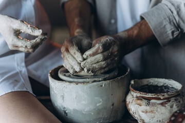 A loving couple in a pottery workshop. Romantic date. Hands in clay.
