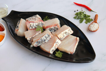 Uncooked boneless pieces of threadfin fish. Raw Dadha fish cubes placed on a black plate. clean...