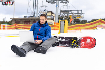 snowboarder typing on the laptop in the mountains winter