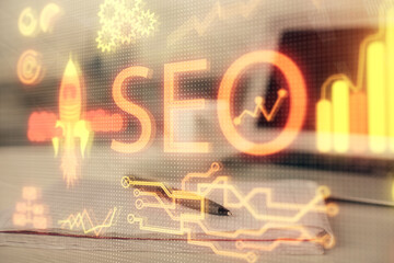 Multi exposure of SEO drawings and desk with open notebook background. Concept of Search optimization