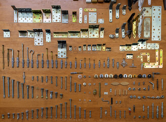 Various fasteners, screws, dowels, metal angles are attached to the board for display, advertising.