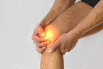Health care concept man suffering from knee pain on light background.