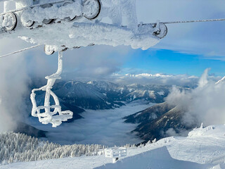 CLOSE UP: Spectacular view of the fog covered valley and a frozen chairlift.