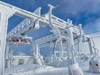 Empty chairlift station and benches are covered in a layer thick ice.