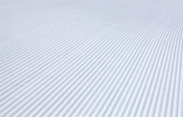 rolled and groomed ski slope, rilled snow background texture in winter