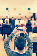 Parents at the performance of children in kindergarten or school. Children on stage. Many parents are watching the kids performance in the hall during holiday. toned