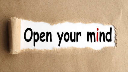 Open your mind ! text on white paper over torn paper background.