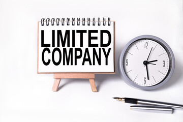 limited company. text on white notepad paper on white background. near the table clock