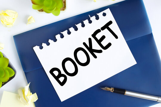 booket . text on white notepad paper on blue folder. on a light background near the crumpled stickers and plants.