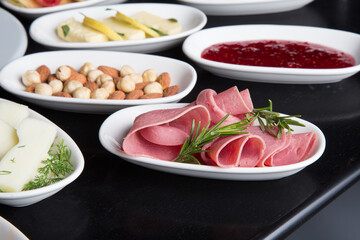 Salami in a white bowl on a breakfast table black background