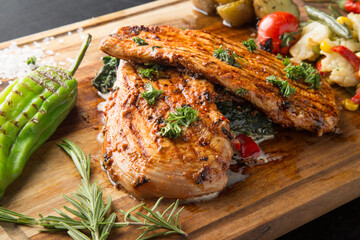 Grilled chicken breast with vegetables on a wooden cutting board