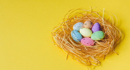 Colorful Easter eggs lie in the nest on a yellow background. The concept of the holiday is Easter, Christ is resurrected. Banner. A place for text. Mock up. View from above. Selective focus.