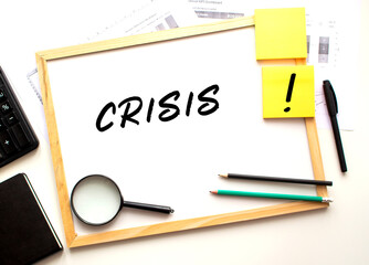 CRISIS text is written on a white office board. Work table with office supplies.