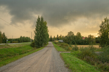 Fototapeta premium threatening sky before heavy downpour during sunset on a dirt road in a rural area