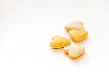 Heart shaped yellow vitamin pills on white background