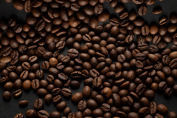 Scattered on surface dark roasted coffee beans background