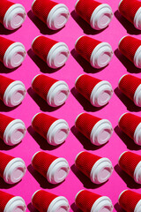 Pasttern, a lot of red paper cups for coffee or tea to go on a pink background. Disposable tableware on a colored background with copy space.