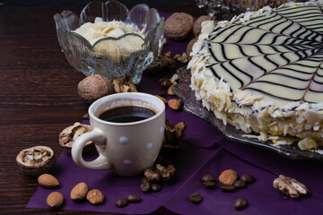Delicious cake with nuts, almonds, black and white chocolate and a cup of coffee on a dark background side view copy space, close up