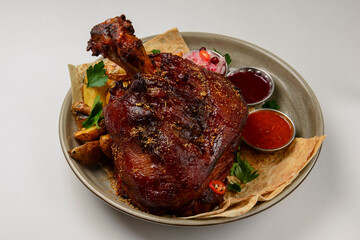 A top steak grilled on a barbecue, served on a plate with two different kinds of sauce over white background.