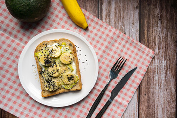 Healthy breakfast toasts with Avocado toast, banana, Yoghurt with whole grain sandwich bread on white dish. Concept of healthy eating, dieting, vegan vegetarian food