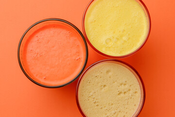 Isolated citrus juice. Three glasses with orange, grapefruit and lemon juice isolated on orange background.