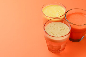 Isolated citrus juice. Three glasses with orange, grapefruit and lemon juice isolated on orange background.