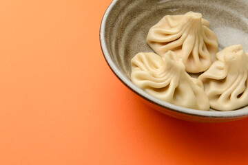 Close up fresh boiled dumplings on ceramic plate. Georgian khinkali food on orange background.