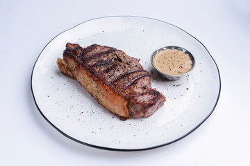 Delicious beef steak with sauce served on a white plate over white background. BBQ meat, barbecue...