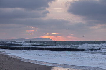 A scenic view of a choppy sea at sunrise with a stormy sky along the Jurassic Unesco world heritage site coastkine