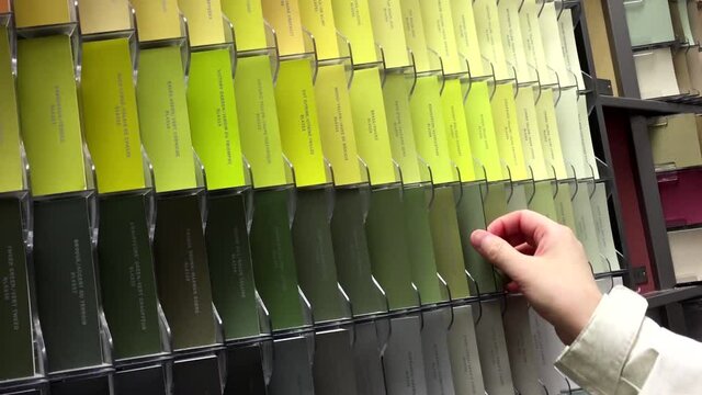 Woman taking some palette color scales inside Home depot store
