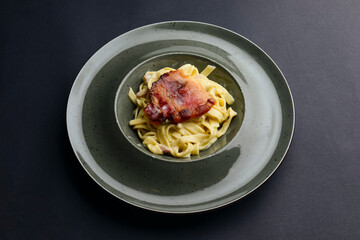 Tagliatelle pasta with steak served in a bowl over black background. Delicious dinner idea.