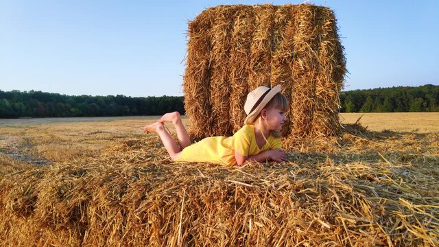 Slow motion. happy little girl lying on haystack