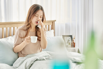 감기와 두통으로 침대에 앉아 있는 여자