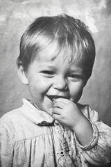 Portrait of little soviet boy holding hand near his mouth, black and white. 1950s. Old surface with...