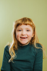 portrait of laughing blonde girl against green background