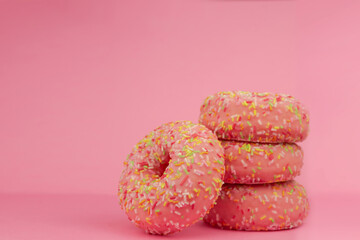 Pink donut on yellow background. Icing sugar sweet food. Colorful snack dessert. Glazed sprinkles. Enjoy a delicious pastry breakfast. Bakery cake. Donut with glaze