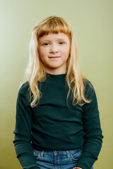 portrait of cute blonde girl against green background