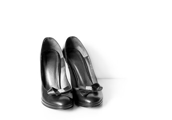 Pair of black ladies shoes on high heels decorated with bow and brooch