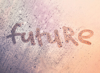 The word future on the window with water drops on sunny background. Fogged window calligraphy. Bright Future concept