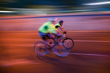 Two blurred cyclists on the road at night
