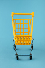 Empty yellow shopping basket on a blue background. Shopping and crisis concept
